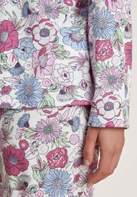 Loungewear met bloemenprint in pastelkleuren; bevat roze, blauwe en groene bloemen op een witte achtergrond. Katoenmengsel, zachte textuur.
