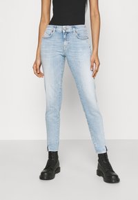 Ljusblå slim fit jeans i denim, med minimal blekning, fem fickor och diskret sömnad, kombinerat med svarta kängor.