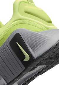 Nike tenisice s gornjim dijelom u limeta zelenoj boji, teksturiranim sivim i crnim potplatom, te crnim detaljima s malim zelenim logotipom.