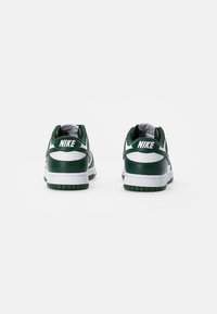 Zapatillas Nike verdes y blancas con un upper de cuero suave, cuello acolchado y suela de goma. Presentan un logotipo bordado en el talón.