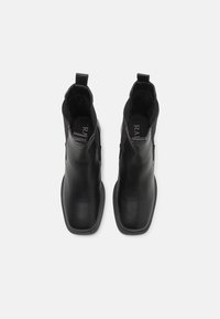 Botas de tornozelo pretas com um acabamento em pele elegante, painéis laterais elásticos e uma aba para puxar. O design de bico quadrado realça a aparência aerodinâmica.