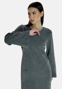 Vestido gris de manga larga con textura acanalada, escote redondo y mangas acampanadas, que presenta una tela suave y lisa.