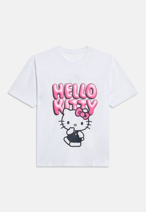 Hvit T-skjorte med rosa "HELLO KITTY" tekst over en tegneserie-katt som har på seg en svart drakt og en rosa sløyfe på hodet.