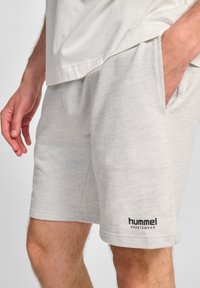 Lichtgrijze katoenen shorts met een ribbelstructuur, zijzakken en zwarte 'hummel' branding nabij de zoom. Relaxte pasvorm en knielange design.