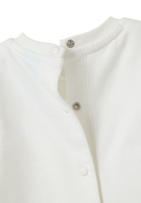 Weißes Baumwollkleidungsstück mit rundem Kragen und Druckknopfverschlüssen am Hals. Glatte Textur, mit einem klaren, minimalistischen Design.