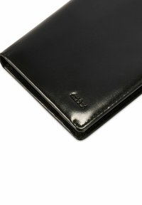 Czarny skórzany portfel o gładkiej fakturze, składanym designie i subtelnym tłoczonym logo. Charakteryzuje się zaokrąglonymi krawędziami i minimalistycznym stylem.