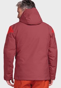 Rote wasserdichte Jacke mit Kapuze, mit kontrastierenden roten Akzenten auf den Schultern. Glatte Textur und taillierte Passform, geeignet für Outdoor-Aktivitäten.