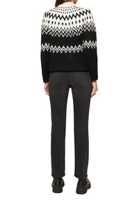 Zwart-wit gebreid sweater met een chevronpatroon, gecombineerd met strakke zwarte jeans en zwarte enkellaarsjes.