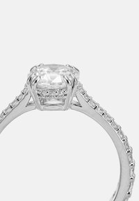 Silberner Verlobungsring mit einem großen ovalen Diamant-Zentrum, umgeben von kleineren Diamanten entlang des Rings, mit einer polierten Oberfläche.