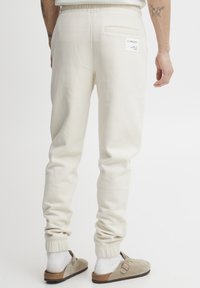 Crèmekleurige sweatpants met een slim fit, geribbelde boorden en een achterzak. Gemaakt van zacht materiaal, met een label aan de rechterkant.