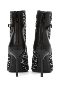 Mustad mustad kingad stilletokontsaga, millel on tekstuurne muster ja hõbedased kaunistused. Taga luku sulgemine. Elegantne disain.