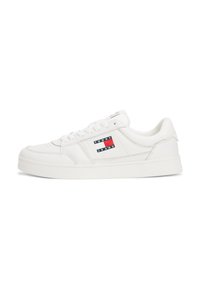 Baskets blanches avec une finition en cuir lisse, dotées d'un col rembourré, d'une fermeture à lacets et d'un écusson en rouge, blanc et bleu sur le côté.