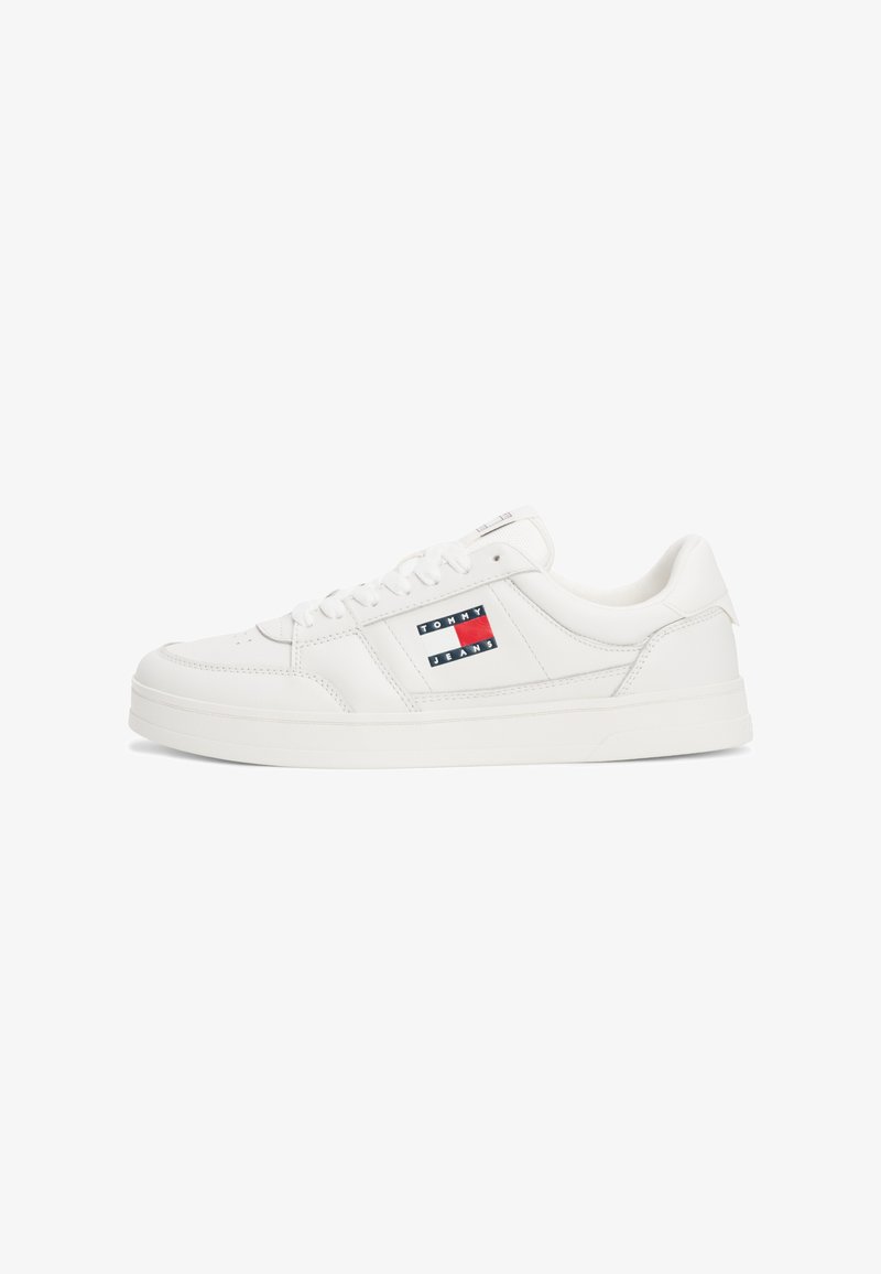 Baskets blanches avec une finition en cuir lisse, dotées d'un col rembourré, d'une fermeture à lacets et d'un écusson en rouge, blanc et bleu sur le côté.
