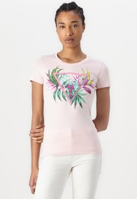 Šviesiai rožinė aptempta marškinėlių suapvalinta iš medvilnės, su trikampiu grafiniu motyvu, kuriame yra žali ir rožiniai lapai bei "GUESS" logotipas centre.