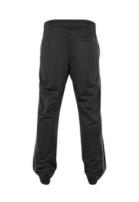 Pantaloni sport negri cu o textură netedă; dotati cu dungi laterale albe și un buzunar pe spate. Banda elastică la talie pentru confort.