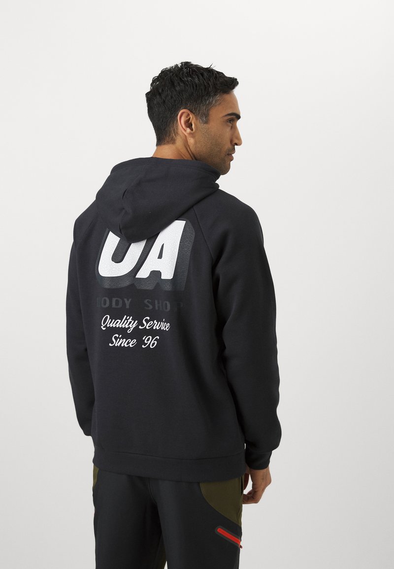 Sweatshirt noir avec un grand logo blanc "UA" au dos, le texte "Qualité Service Depuis '96" en dessous, et une finition texturée.