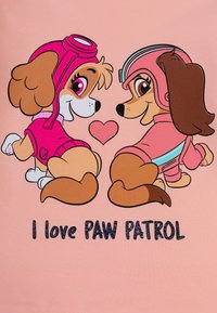Tessuto rosa con due cani dei cartoni animati dal pelo marrone, entrambi vestiti con outfit rosa, circondati da un cuore e dalla scritta "I love PAW PATROL."