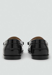 Musta nahkakengät, joissa on sileä pinta, pyöreä kärki ja koristeelliset ompeleet kantapäässä. Klassinen muotoilu, jossa on vähän metalliosia.