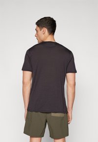 T-shirt corto grigio scuro realizzato in un tessuto morbido, con colletto a girocollo e una vestibilità comoda, abbinato a pantaloni corti verdi.