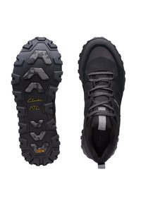 Zapatos de exterior negros con una suela texturizada y resistente, y cordones reflectantes. La parte superior cuenta con acentos de malla y una puntera reforzada para mayor durabilidad.