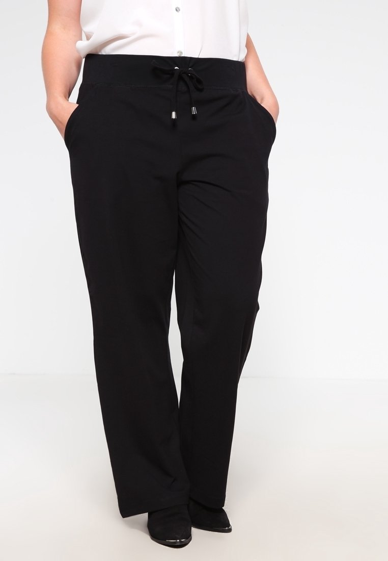 Svarta, vida byxor med mjuk textur, elastisk midja, justerbar dragsko och sidfickor, utformade för komfort och enkelhet.