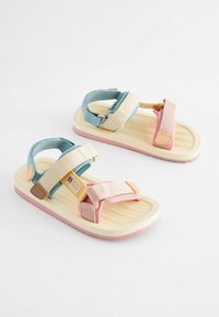 Bunte Sandalen mit einem hellgelben Grund, pinken und blauen Riemen, strukturiertem Fußbett mit Zickzackmuster und verstellbaren Verschlüssen.
