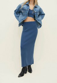 Blauw geribd gebreid cropped top gecombineerd met een bijpassende lange rok. Draag met een cropped spijkerjack en zwarte enkellaarzen.