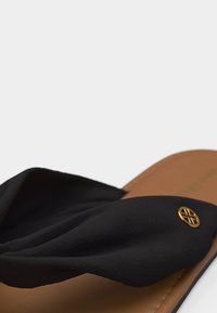 Μαύρο δερμάτινο σανδάλι με καφέ σόλα και μικρό στρογγυλό χρυσό λογότυπο στο λουράκι.