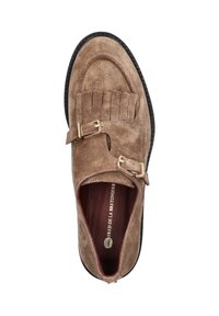 Bruine suède moccasin-stijl schoen met twee gouden gespen, franjes en een ronde neus. Zwarte rubberen zool met gestructureerd oppervlak.