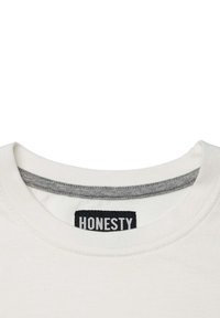 Hvid T-shirt med en rund halsudskæring og grå indvendig kant. Sort "HONESTY" label synlig på kraven. Blødt bomuldsstof.