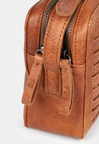 Borsa in pelle marrone con superficie testurizzata, dotata di una zip superiore, due linguette di apertura e cuciture verticali su un lato.