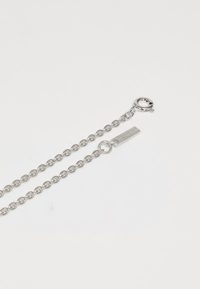 Ασημένια αλυσίδα κολιέ με κυκλικούς συνδέσμους, διαθέτοντας κλιπ αστακού και λεπτομέρειες σε ορθογώνια ετικέτα. Λείος υφή και μεταλλικό φινίρισμα.