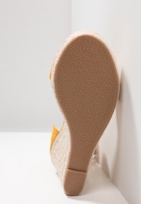 Klínová obuv s strukturovaným béžovým textilním svrškem a žlutým akcentem. Podešev je gumová s vzorovaným gripem, velikost 37.