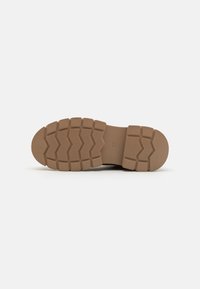 Semelle extérieure en caoutchouc marron avec un motif de semelle en zigzag, présentant une pointe arrondie et une surface texturée pour l'adhérence et la durabilité.