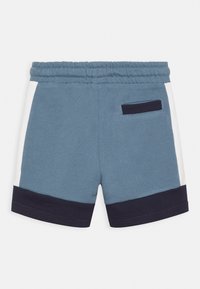 Calções de algodão azuis com painéis laterais azul-marinho e brancos, cintura elástica e um bolso nas costas. Textura suave e design casual.