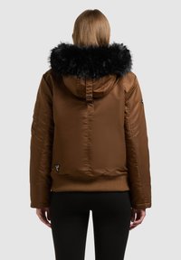Hnědá prošívaná bunda s černou kapucí lemovanou kožešinou, s žebrovaným lemem a manžetami, bočními kapsami a logovou nášivkou v levé dolní části.