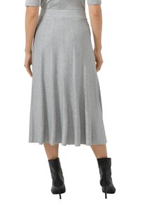 Szara plisowana spódnica midi o gładkiej fakturze, z paskiem w talii. Noszona z czarnymi botkami za kostkę, podkreślającymi lekkość spódnicy.