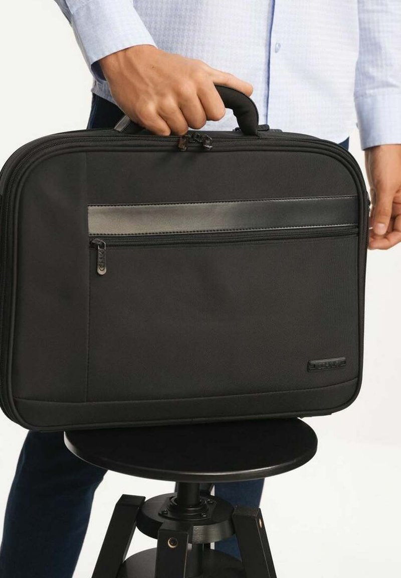 Czarna torba na laptopa z górną rączką, wykonana z trwałego materiału. Posiada przednią kieszeń na zamek błyskawiczny oraz gładki, szary pasek akcentujący.