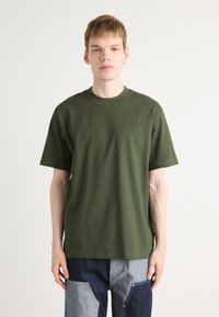 Olivgrünes Baumwoll-T-Shirt mit Rundhalsausschnitt und kurzen Ärmeln, mit dezentem Branding auf der Brust. Einfaches, lässiges Design.