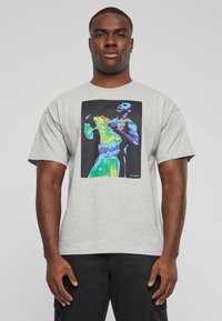 Camiseta de algodón gris con una vibrante obra de arte térmica de dos figuras sobre un fondo negro. Mangas cortas y un ajuste relajado.