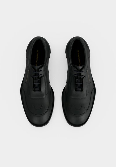 Ζευγάρι μαύρα δερμάτινα οξφορντ με στρογγυλευμένες τετράγωνες μύτες, σε λευκό απλό φόντο, από πάνω.