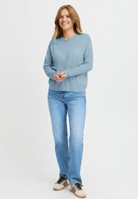 Ljusblus, långärmad, rundhalsad topp i ett mjukt material. Såld tillsammans med ljusblå jeans och svarta och krämfärgade sneakers. Enkel design.