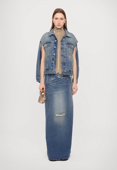 Denim jacket with raw edges over a beige turtleneck, paired with a long denim skirt featuring a ripped detail and a small patterned bag.