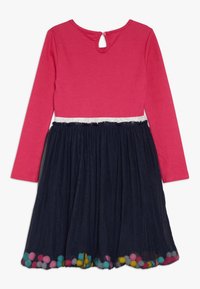 Pitkähihaista mekkoa, jossa on vaaleanpunainen yläosa ja laivastonsininen tüllihame, hopeinen vyötärö ja helma, joka on koristeltu värikkäillä pompomeilla. Avaus selässä avaimenreiällä.