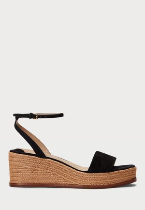 Sandali con zeppa in suede nera, presentano una piattaforma in juta intrecciata, con una tracolla piatta e un cinturino alla caviglia regolabile con fibbia metallica.
