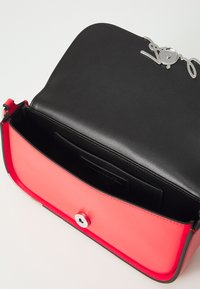 Borsa a mano in pelle nera con una parte inferiore in pelle rossa, accessori in metallo argentato, chiusura magnetica e una tasca interna visibile.