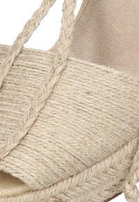 Sandalia cuña de fibra natural con parte superior de yute trenzado, forro textil beige y tiras trenzadas, con una superficie texturizada y diseño de punta abierta.