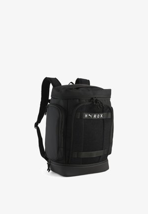 Sac à dos noir Puma avec plusieurs compartiments zippés, bretelles rembourrées et logo "HYROX" sur le panneau avant.