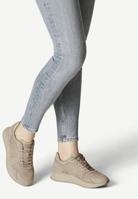 Světlé béžové sneakers s hladkým semišovým povrchem, s designem na šněrování, jemným prošíváním a silnou, strukturovanou podešví.