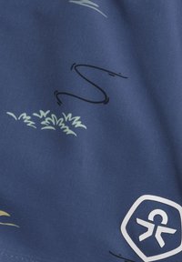 Mörkblått tyg med abstrakta ljusgr öna och svarta mönster, med en vit logotyp i en hexagon i det nedre högra hörnet.